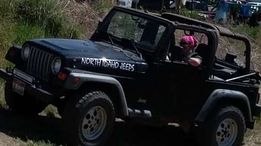 Girl in a black Jeep TJ rolling over logs
